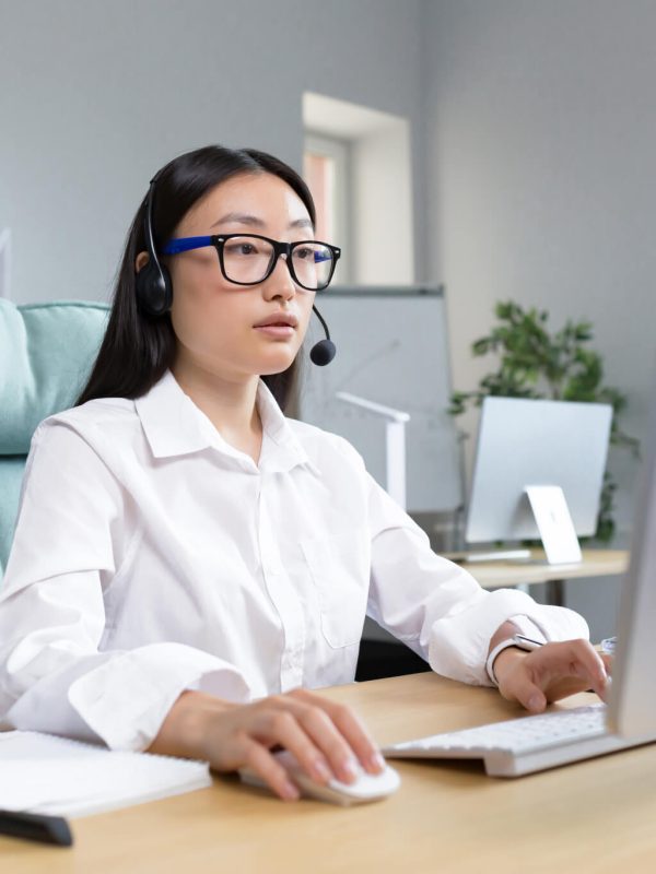 online-distance-learning-asian-teacher-in-headphones-sitting-at-a-table-teaching-a-lesson-online.jpg